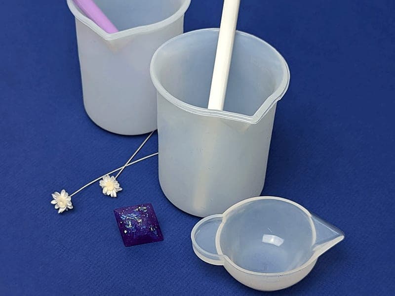 Mixing cups, a stir stick and dried flowers laid out for casting