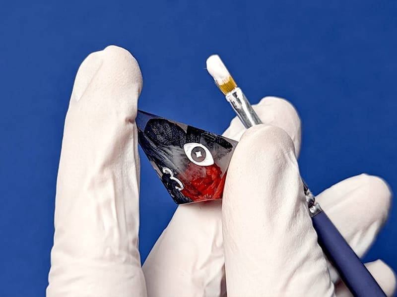 Inking the numbers of a red and clear D4 with a fine brush
