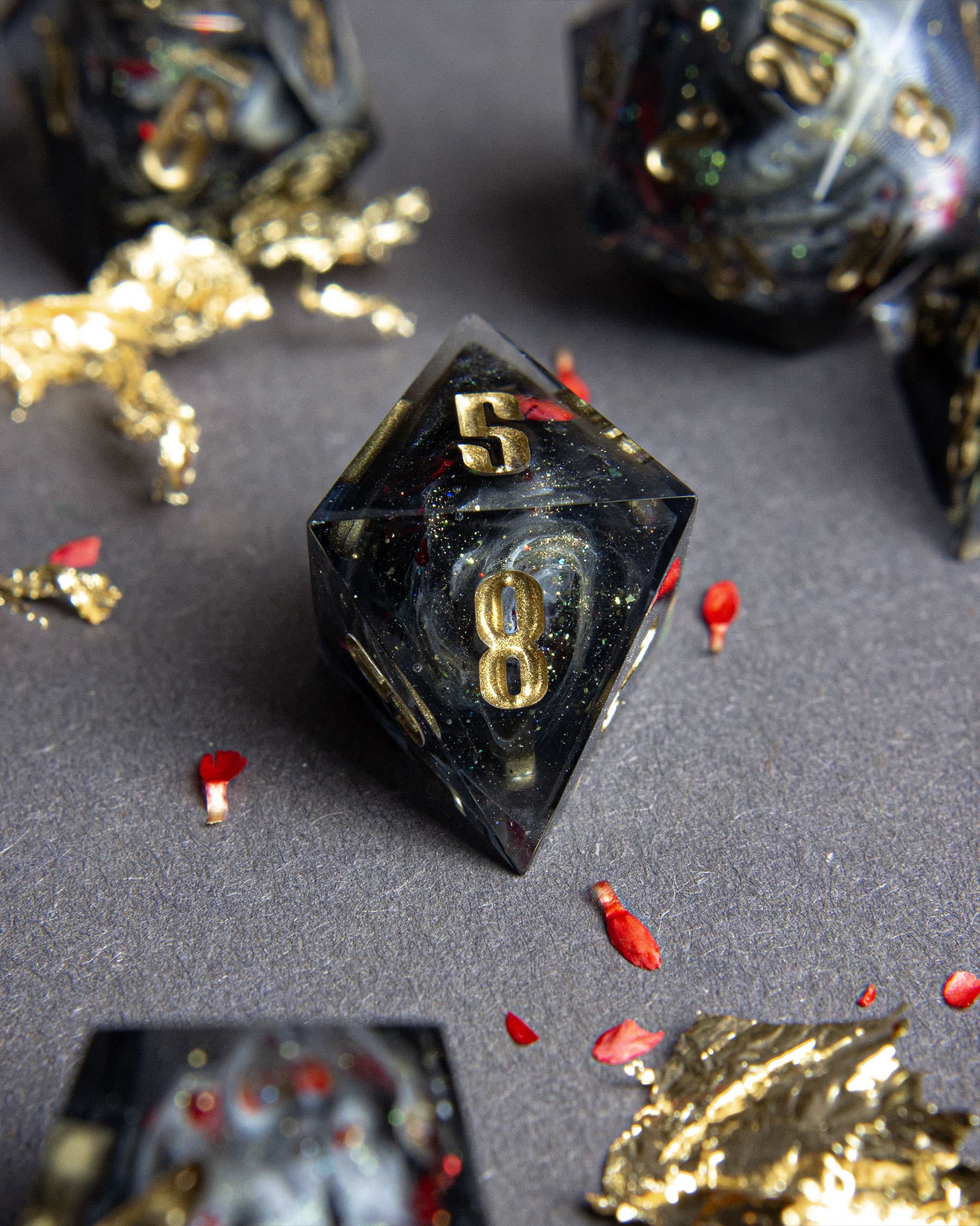 The Last Gommage D8, black resin with gray swirls, red flower petals, metallic foil, and golden numbers